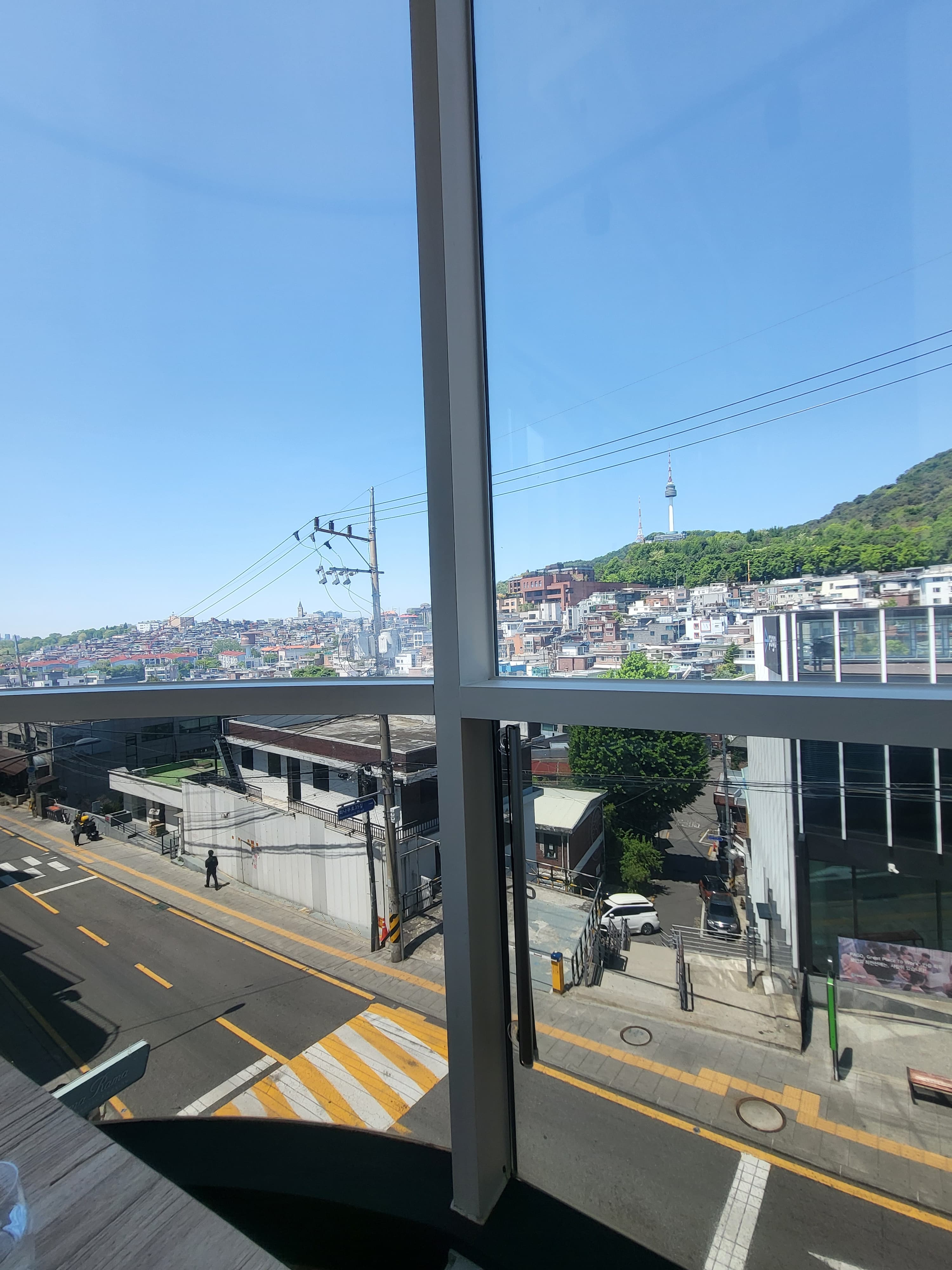 창가 좌석 — 통유리 너머로 거리와 N서울타워가 보인다