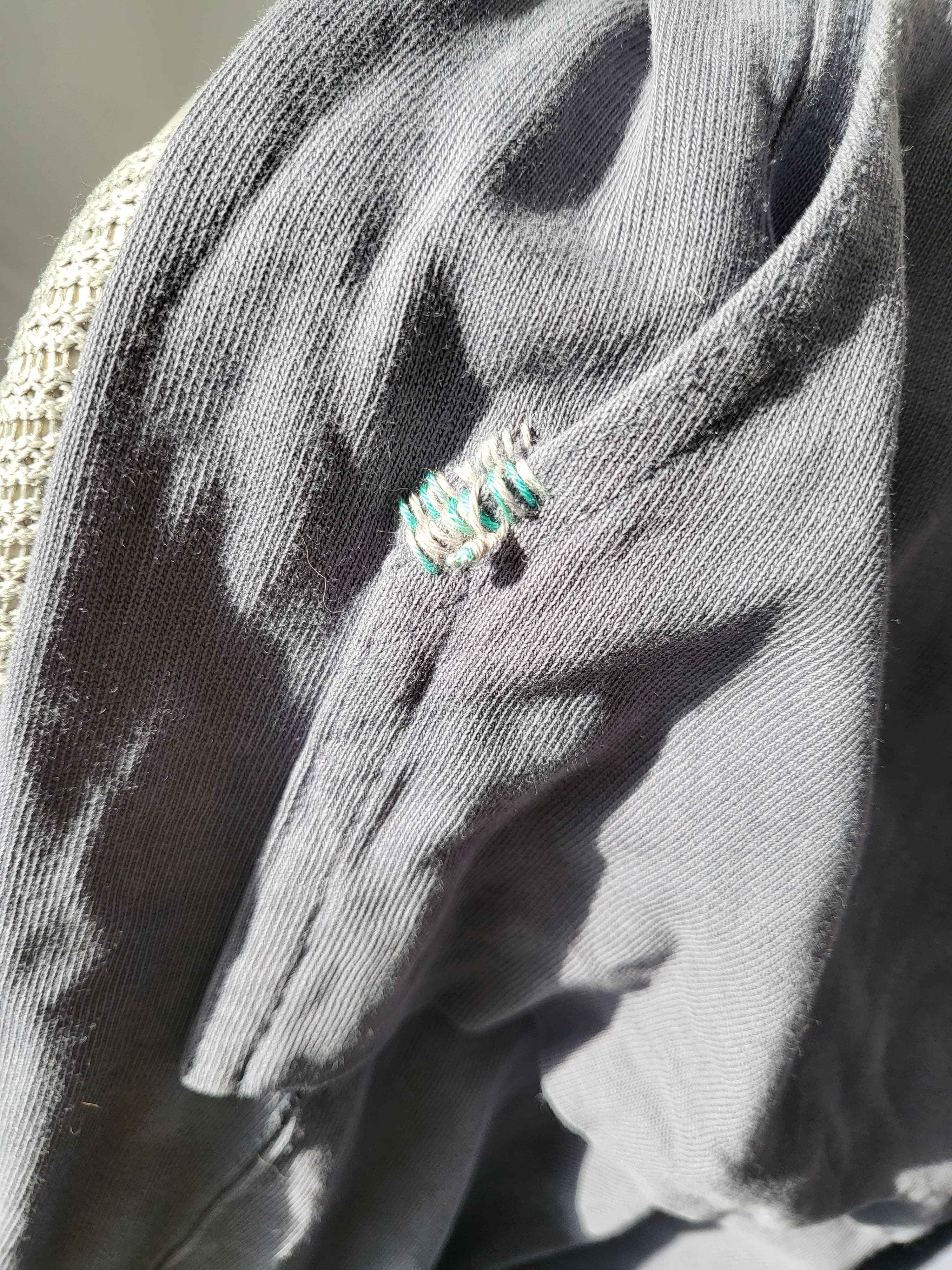 Blanket stitch close-up — the mended mark in sunlight