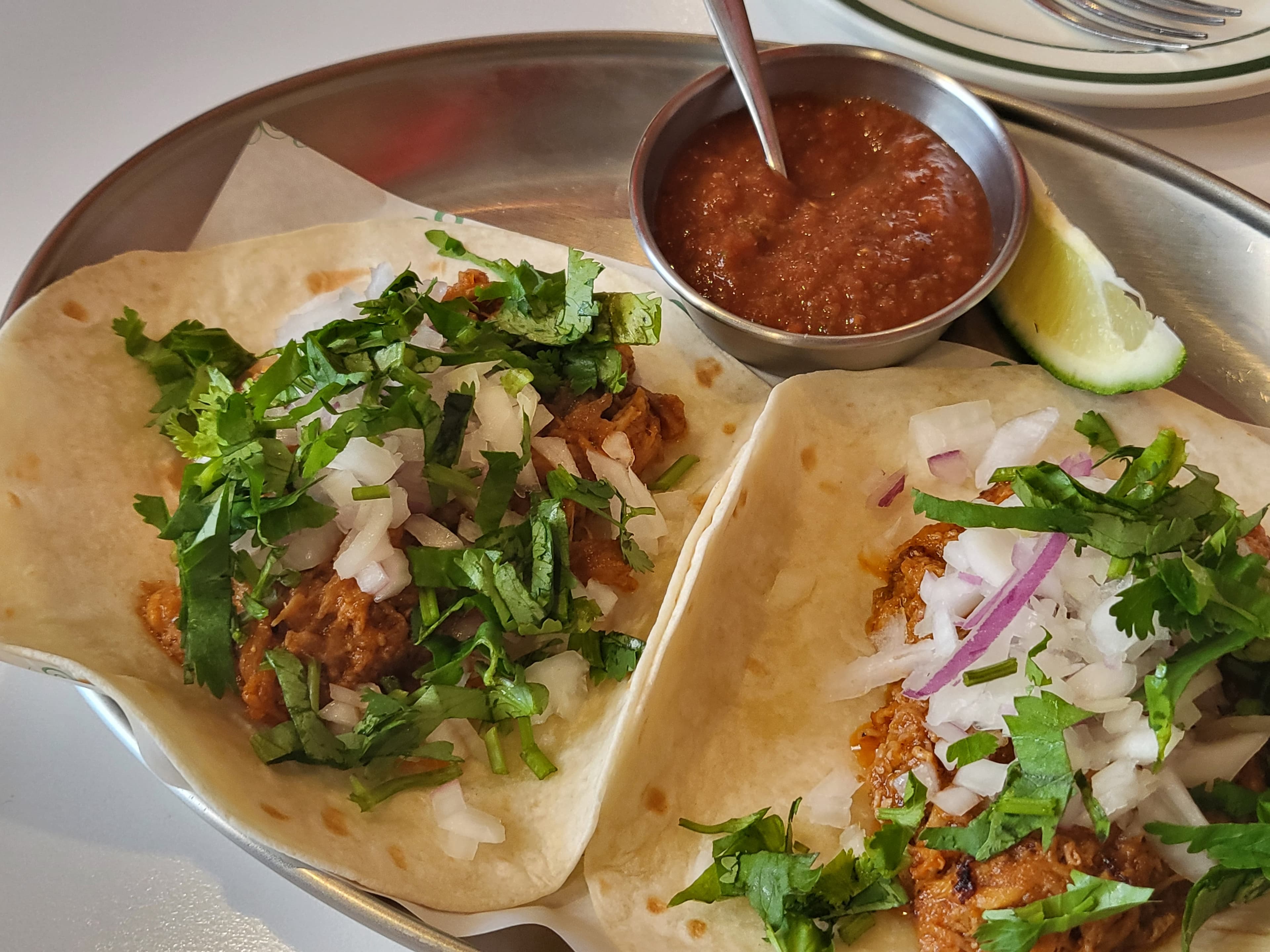 Tacodot jerk chicken tacos — flour tortilla with onion and cilantro